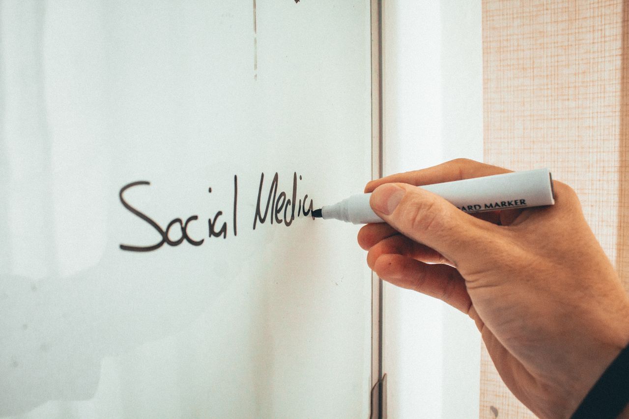 Anonymous male instructor writing on a whiteboard with a marker during social media training sessions